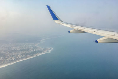 Aerial view of airplane flying over sea against sky
