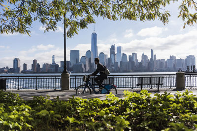 Usa, man on bicycle at new jersey waterfront with view to manhattan