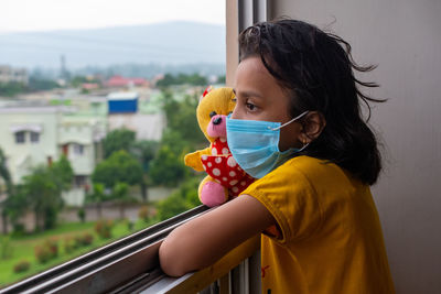 Portrait of a girl looking through window