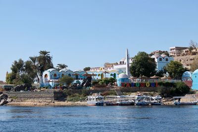 Buildings by river against blue sky