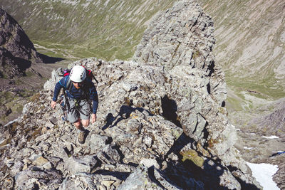 High angle view of hiker wearing helmets while climbing mountain