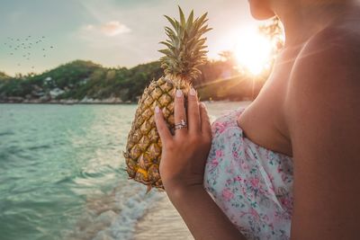 Close-up of woman holding ice cream at beach against sky