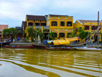 Boats in river against buildings in city