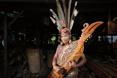 Portrait of woman wearing traditional dress holding sape at warehouse