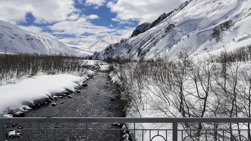 View of the mountains by the river from the bridge in winter