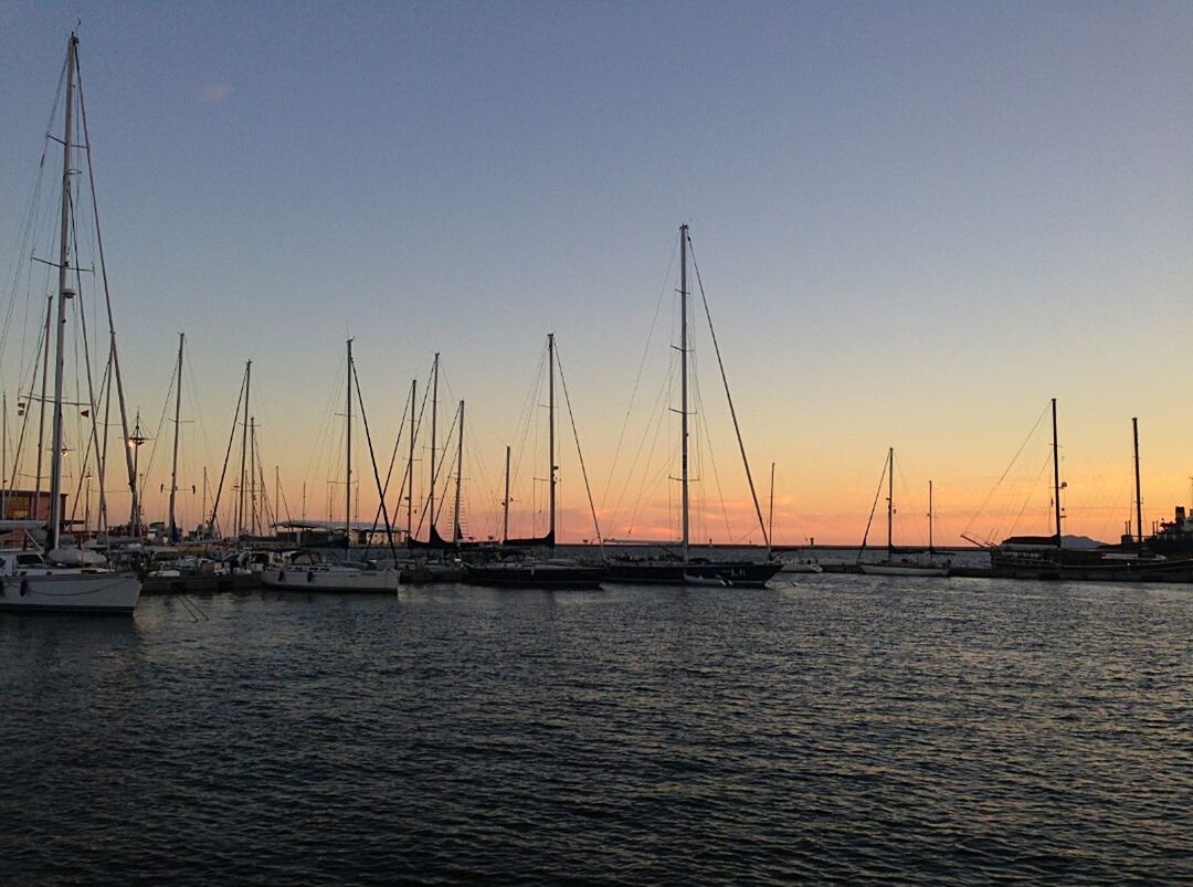 SAILBOATS IN SEA AT SUNSET