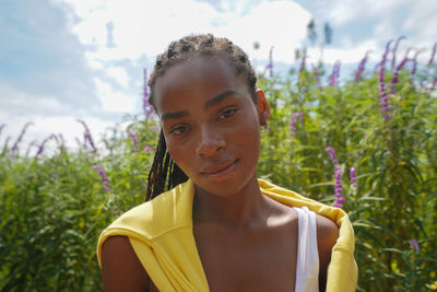 Portrait of young woman standing against plants