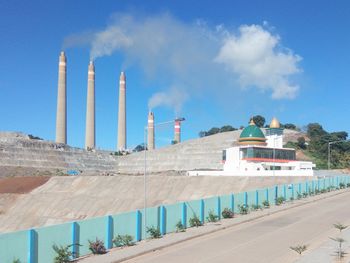 Panoramic view of factory by building against sky