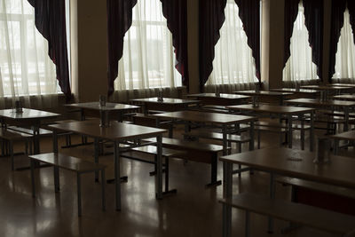 Dark hall with tables. curtains on window. canteen in school.