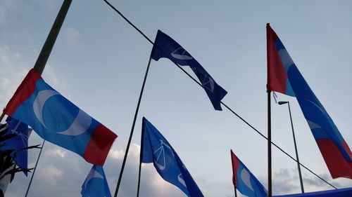 Low angle view of flags against sky