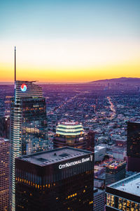 Illuminated cityscape against sky during sunset