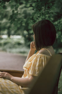 Side view of woman with short hair sitting on bench in park