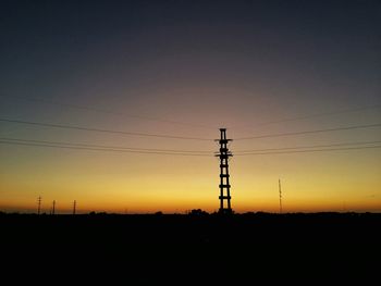 Electricity pylon on landscape against sunset sky