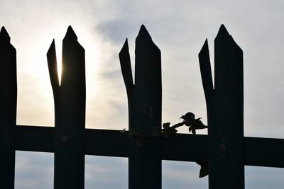 Low angle view of silhouette fence against sky during sunset