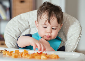 Close up of toddler eating mandarins in his high chair