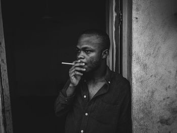 Young man smoking a cigarette against the wall.