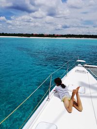 Rear view of man sitting on boat in sea against sky