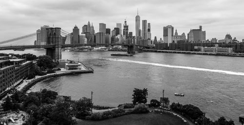 Brooklyn bridge over east river against sky in city