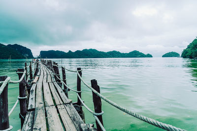 Wooden posts in lake against sky