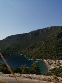 Scenic view of river by mountains against clear blue sky