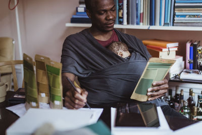 Male entrepreneur writing on paper while working at home office