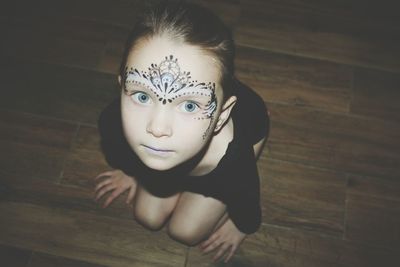 High angle portrait of girl with face paint sitting on floor