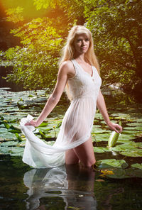 Portrait of young woman standing against lake