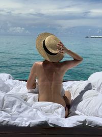 Woman wearing hat on sea shore against sky