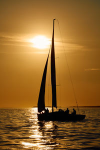 Sailboat sailing on sea against sky during sunset
