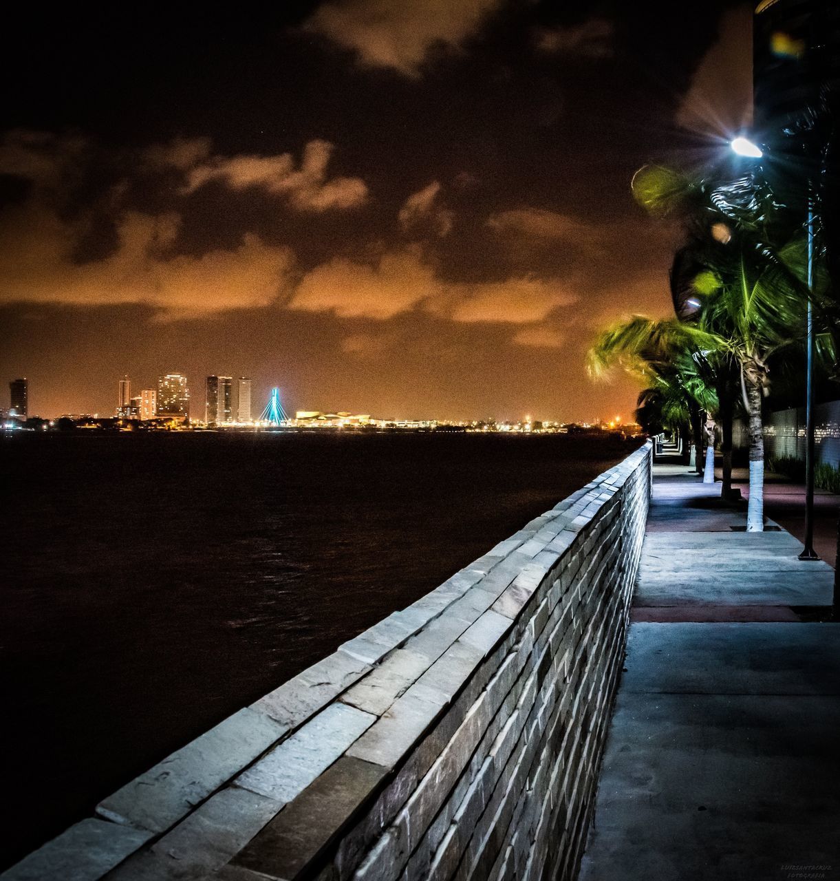 ILLUMINATED STREET LIGHT BY SEA AGAINST SKY