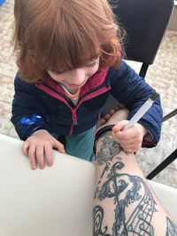 High angle view of boy drawing tattoo