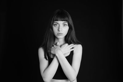 Portrait of young woman against black background