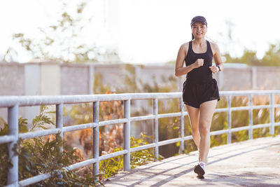 Full length of young woman running on railing