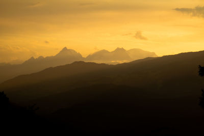 Scenic view of silhouette mountains against orange sky