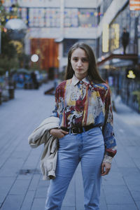 Portrait of young woman standing in city