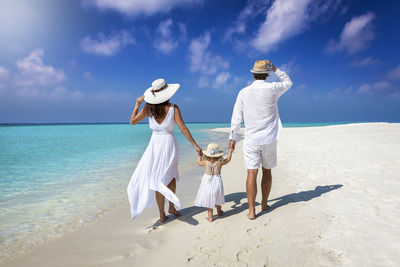 Family walking on beach against sky