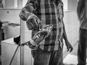 Midsection of man holding dead fish in market