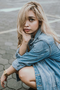 Portrait of beautiful young woman crouching on street