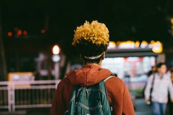REAR VIEW OF MAN AND WOMAN STANDING AGAINST ILLUMINATED LIGHTS