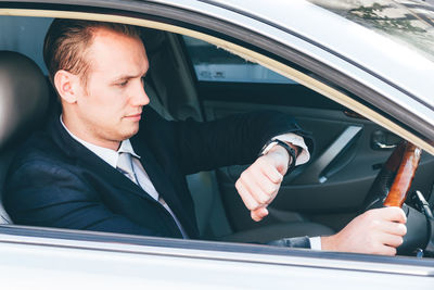 Businessman checking time while driving car