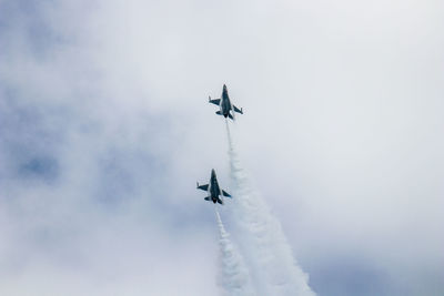 Low angle view of airshow against cloudy sky