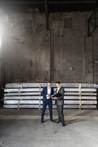 Two businessmen with folder talking in an old storehouse