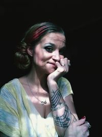 Portrait of mid adult woman with hand on chin sitting at darkroom