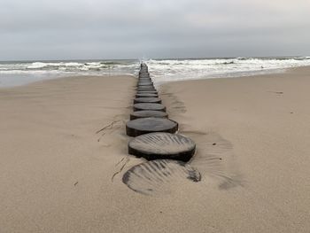 Wooden posts on beach against sky