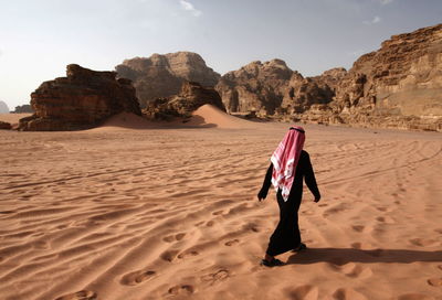 Rear view of man walking at desert
