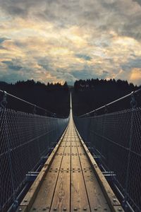 Rope bridge against sky during sunset