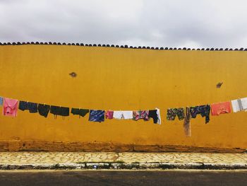 Clothes drying outdoors against yellow wall