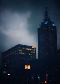 Illuminated buildings in city against sky at dusk