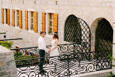 Woman with umbrella on railing of building