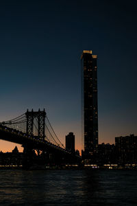 Illuminated bridge over river against sky at night